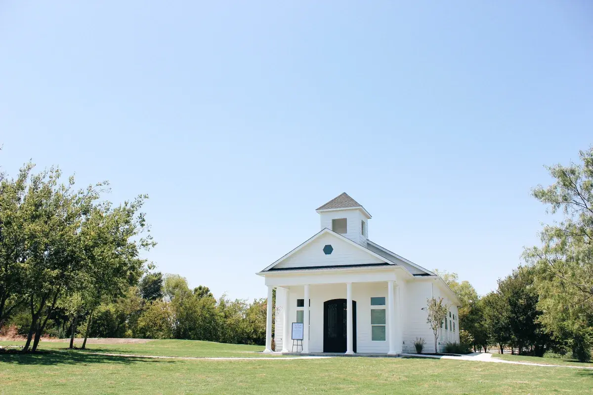 White chapel exterior with columned entrance and surrounding lawn